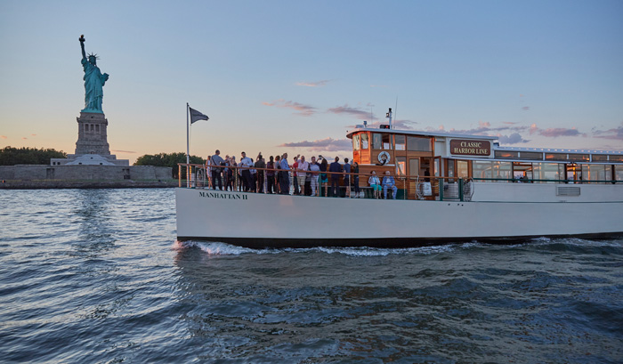Sunset Cruise with guests on the bow of yacht Manhattan II at the Statue of Liberty